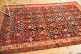 Malayer vintage rug displaying allover tangerine and blush floral motifs with a subtle, even texture on dark navy.