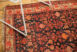 Malayer rug corner with tangerine, blush, ivory floral pattern on dark navy ground.