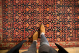 Vintage Malayer rug's textured pile and repeating floral design in dark navy, tangerine, blush.