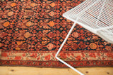 Malayer rug corner detail: ivory floral border, dark blue field, and lightly tattered end.