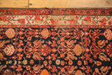 Vintage Malayer rug's red and neutral borders meeting a dense floral navy field.