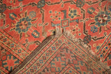 Folded antique Beshir rug, showing hand-knotted foundation, red geometric pattern, tattered ends.