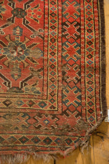 Tattered corner of the Antique Beshir carpet, showing worn fringe and madder red geometric patterns.