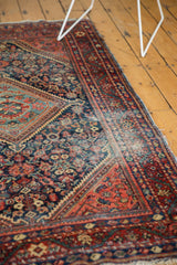 Aged cherry red border and faded navy field with tattered edge on a vintage Mahal rug.