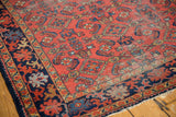 Vintage Lilihan rug corner, cherry red Herati field, navy floral border, visible low pile.