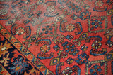 Close-up of vintage Lilihan rug with worn madder red pile and floating Herati motifs.