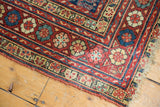 Northwest Persian rug corner with cherry red border, ivory, blue, gold floral patterns, and natural fringe.