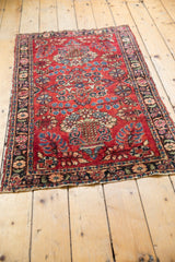 Lilihan rug corner showing raspberry red field, floral motifs, scattered white knots, and secured tatter.