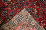 Dense floral arabesques, red, blue, white knots, and tattered side of a folded Lilihan rug.