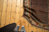 Vintage Hamadan rug's navy boteh pattern, burnt orange border, and storied worn edge.