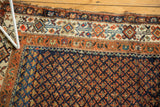 Vintage Hamadan rug featuring navy boteh field, pale tangerine and ivory geometric borders, worn edge.