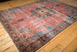 Intricate tendrils and floral blossoms on the raspberry red field of an antique Farahan Sarouk rug.
