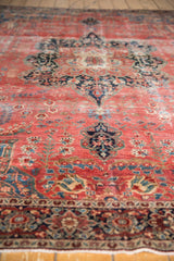 Antique Farahan Sarouk's raspberry red field, delicate floral tendrils, navy border, and ivory fringe.