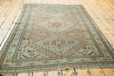 Distressed vintage Shiraz rug corner, featuring geometric patterns and soft seafoam and copper tones.