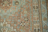 Textured close-up of vintage Shiraz rug's copper, sea foam, and terracotta floral motifs.