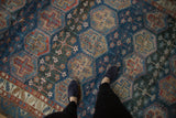 Distressed vintage Baktiari carpet detail: hexagonal panels in blue, red, sand, and charcoal tones.