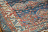 Distressed vintage Baktiari carpet, showing low pile texture and sky blue, cherry red geometric motifs.