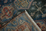 Distressed Baktiari rug corner showing hand-knotted reverse, blue, red geometric pattern, and fringe.