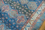 Distressed Baktiari rug detail, featuring geometric panel design, tribal border, and worn blue, red, beige tones.