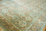 Distressed vintage Baktiari carpet corner with garden patterns in terracotta, blush, and slate blue.