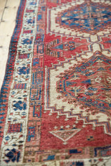 Vintage Serab runner's geometric side border in cherry red, camel, and navy blue, showing pile texture.