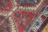 Geometric patterns and textured pile of vintage Serab rug, cherry red, camel, and blue.