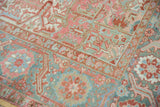 Heriz carpet close-up showing distressed pile with geometric palmettes and vinery in blush, seafoam green, ivory.