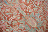 Distressed vintage Heriz carpet close-up showcasing rectilinear vinery and palmettes in cherry red, sea foam, and blush.