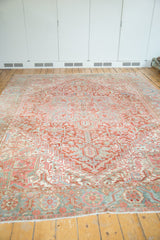 Distressed Heriz rug corner, faded red, sea foam green geometric palmette border, visible pile wear.