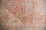 Distressed vintage Heriz carpet detail featuring faded cherry red and sea foam geometric vinery.