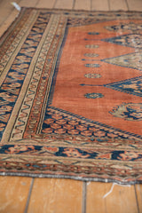 Malayer rug's dusty rust blush field showing wear, contrasting navy blue and ivory patterned border.