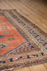 Persian Malayer rug's worn rust blush field and navy geometric patterned border, showing stable selvage.