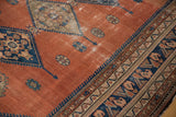 Vintage Malayer rug detail: dusty rust field, navy blue border, and visible foundation wear.