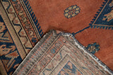 Worn dusty rust Malayer rug pile with navy details, revealing hand-knotted reverse foundation.