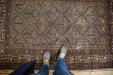 Distressed vintage Malayer rug showing germinating plant lattice, clover motifs, and pile wear.