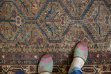 Distressed vintage Malayer rug pile, featuring worn camel brown, sky blue, and blush geometric patterns.