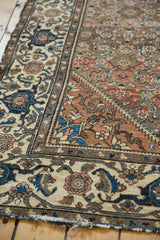 Distressed vintage Malayer rug corner with wide beige border, navy and rust turtle samovar motifs.