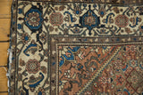 Corner of distressed Malayer rug, showing greige Herati pattern, rust field, and low pile.