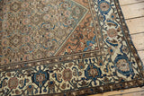Distressed Malayer rug corner featuring muted Herati field and navy, rust turtle samovar border.