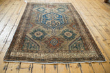 Distressed Malayer rug's intricate floral palmettes with navy, teal, and terracotta tones.