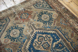 Distressed Malayer rug close-up showing worn navy and terracotta floral palmettes.