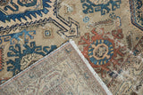 Vintage distressed Malayer rug detail: worn pile, folded to reveal beige foundation, fringe.