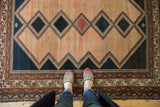 Malayer rug's distinct navy and ivory geometric diamonds, faded red border, and even wear.