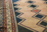 Antique distressed Malayer rug showing faded raspberry, navy diamond motifs and intricate border.