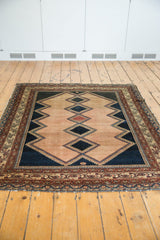 Distressed antique Malayer rug's lower corner, showing worn pile and machine bound end.
