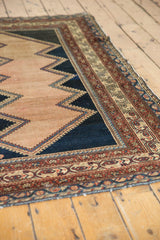 Distressed Malayer rug corner, intricate faded raspberry, ivory borders, dark navy zigzag, visible wear.