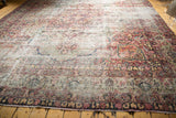 Antique Kerman carpet's floral medallion and multi-band borders in cochineal red and ivory, showing wear.