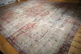 Antique Dilmaghani Kerman rug detail, displaying extensive wear, faded floral arabesques, tattered edge.
