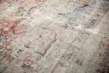 Antique Kerman rug with cochineal red and navy floral arabesques, low pile texture.