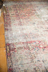 Antique Kerman rug's side with tatter, showing threadbare floral motifs and knot heads.